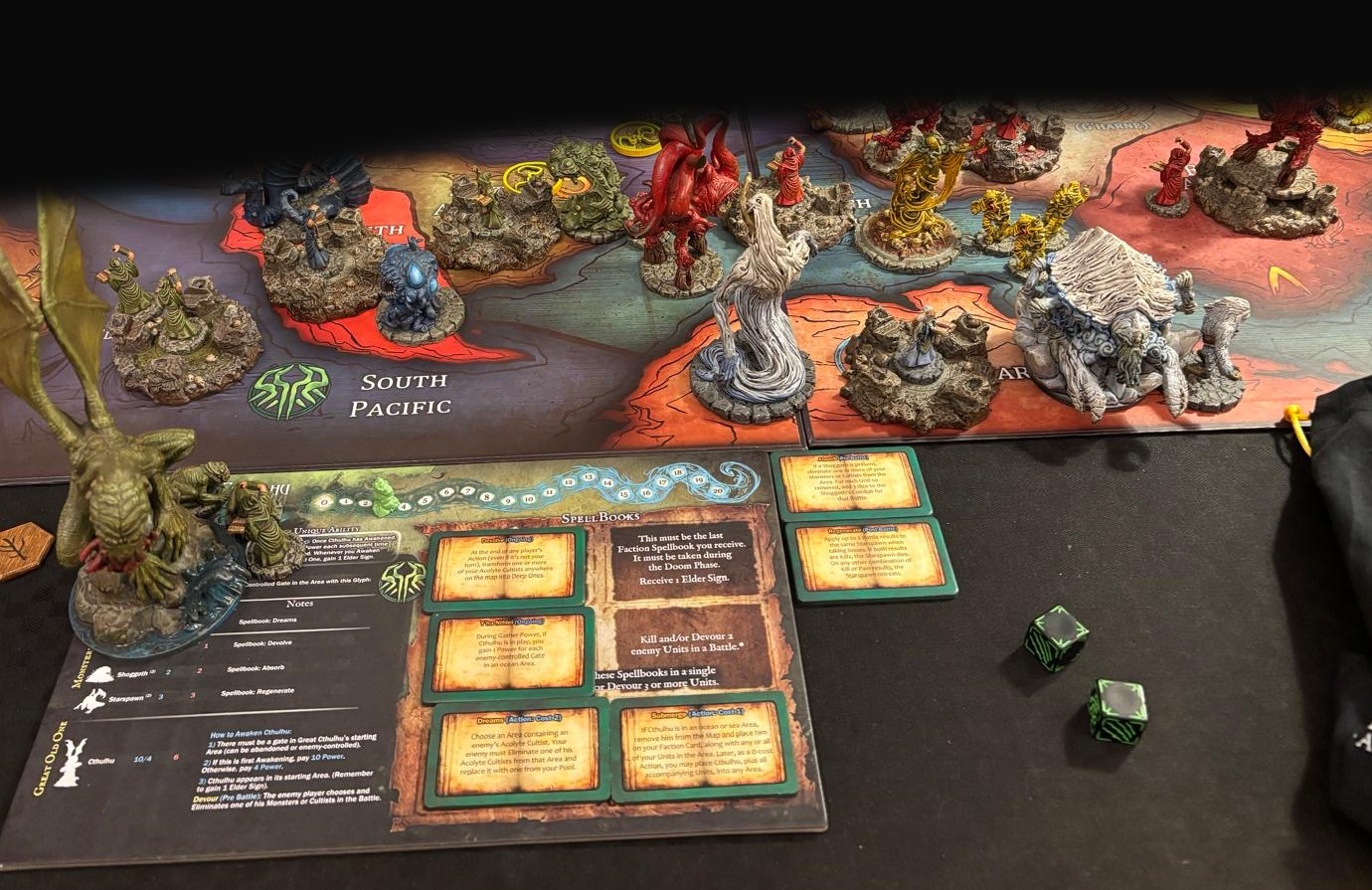 A Cthulhu-style board game in progress with painted monster miniatures on a world map, plus a Great Old One player sheet and dice.