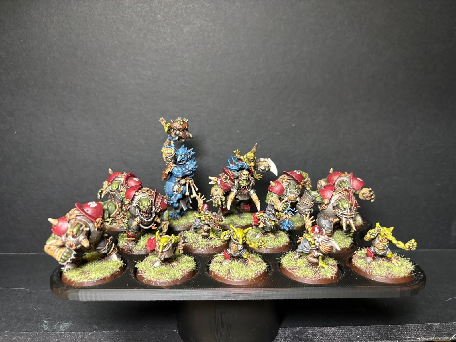 A painted fantasy football team of orcs and goblins arranged on a black display tray.