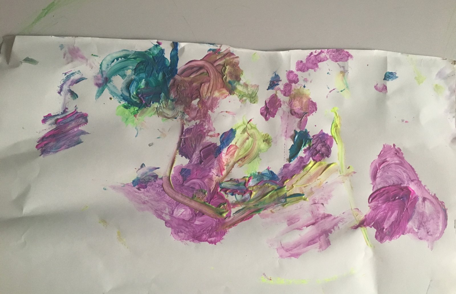 A finger painting of thick swirls and splodges in purple, pink, green and blue on white paper.